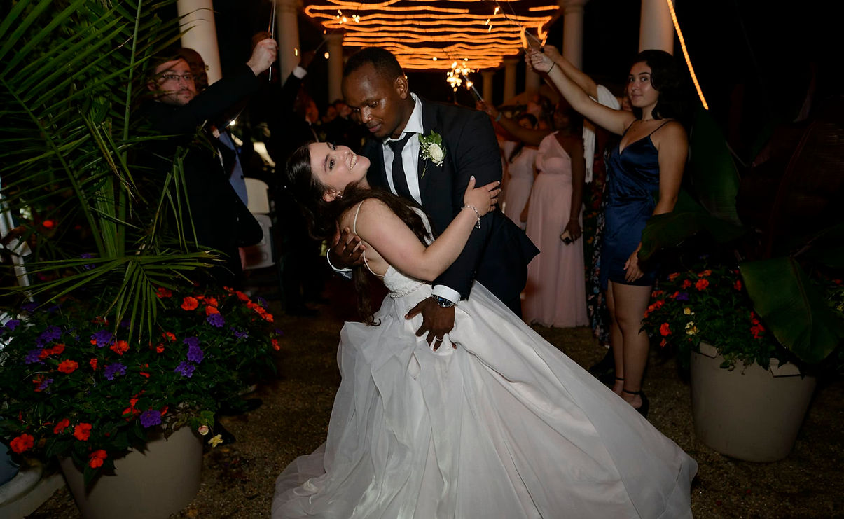 Bride and groom dip beneath sparklers during a nighttime wedding celebration.