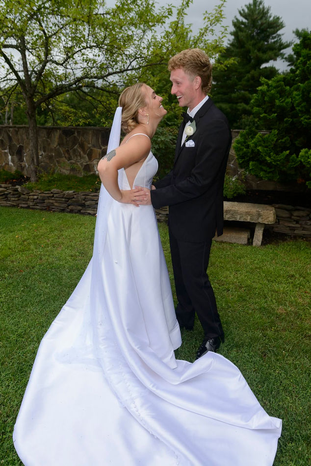 Bride and groom laughing and facing off in the lush garden this full length candid shot.