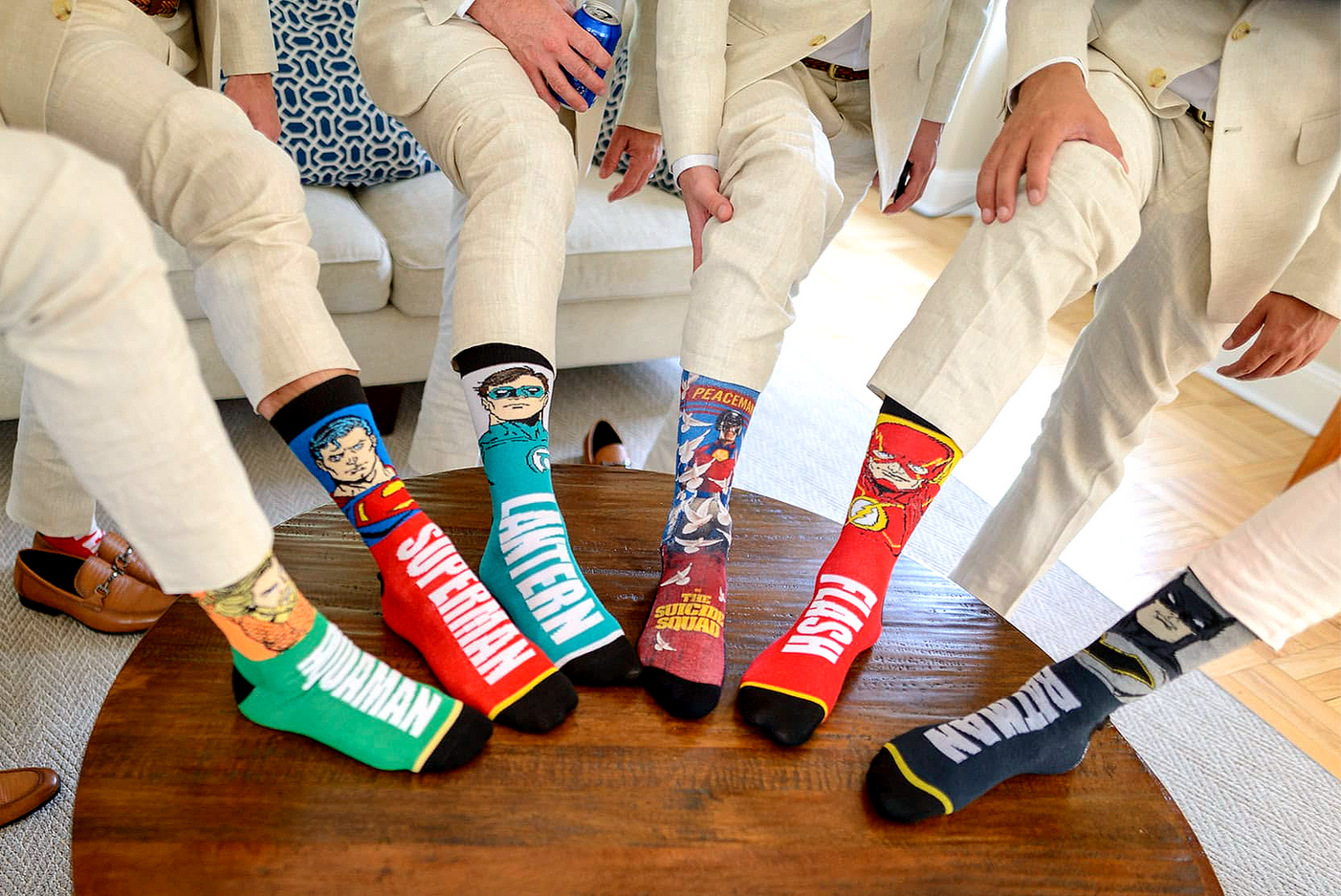 Groomsmen showing colorful superhero socks with feet on a table