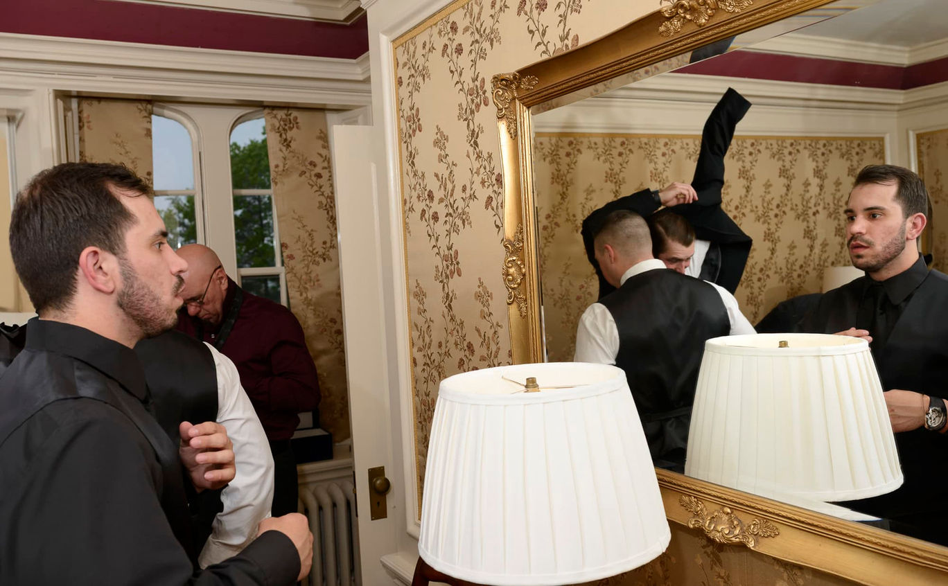 Groom looking at himself in a mirror while getting ready