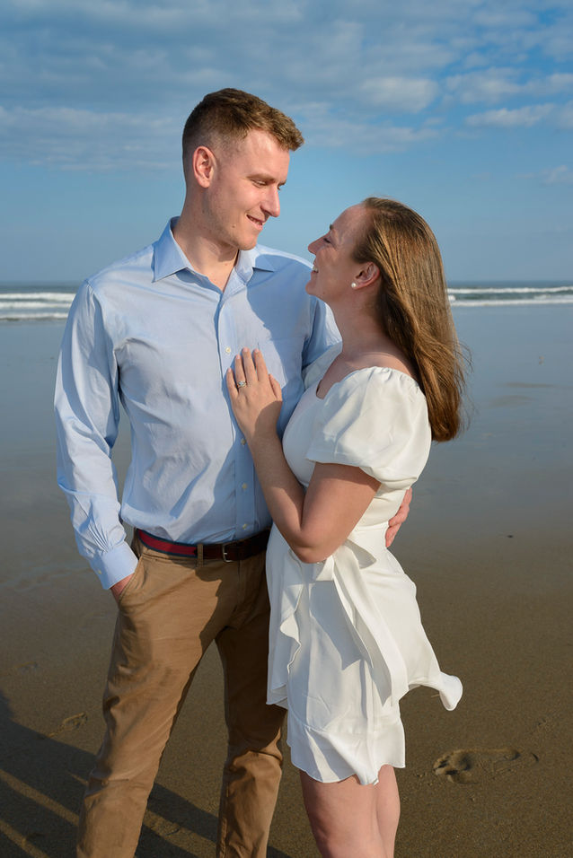 A romantic close-up of the couple gazing into each other's eyes, with the beach waves softly rolling in the background, capturing their intimate connection.