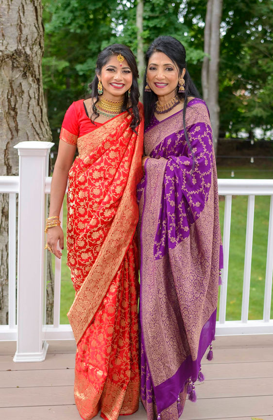 Portrait of the bride and her mother on the deck wearing red and purple sarees.