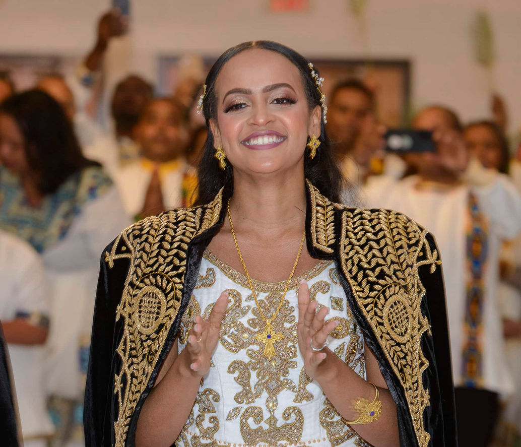 Bride smiling and clapping while dancing Eskista in black and gold cape.