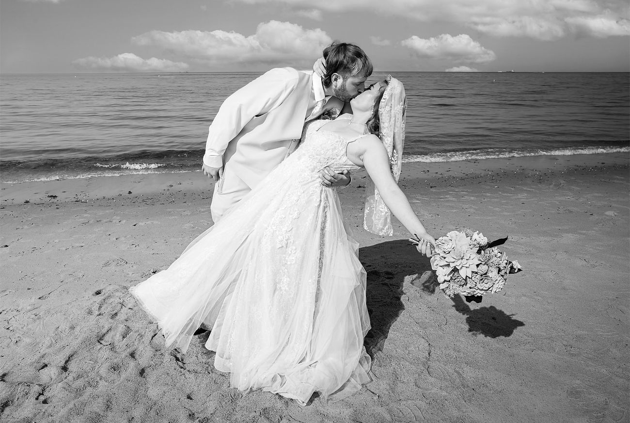 groom-dipping-bride-on-beach-in-black-and-white.jpg