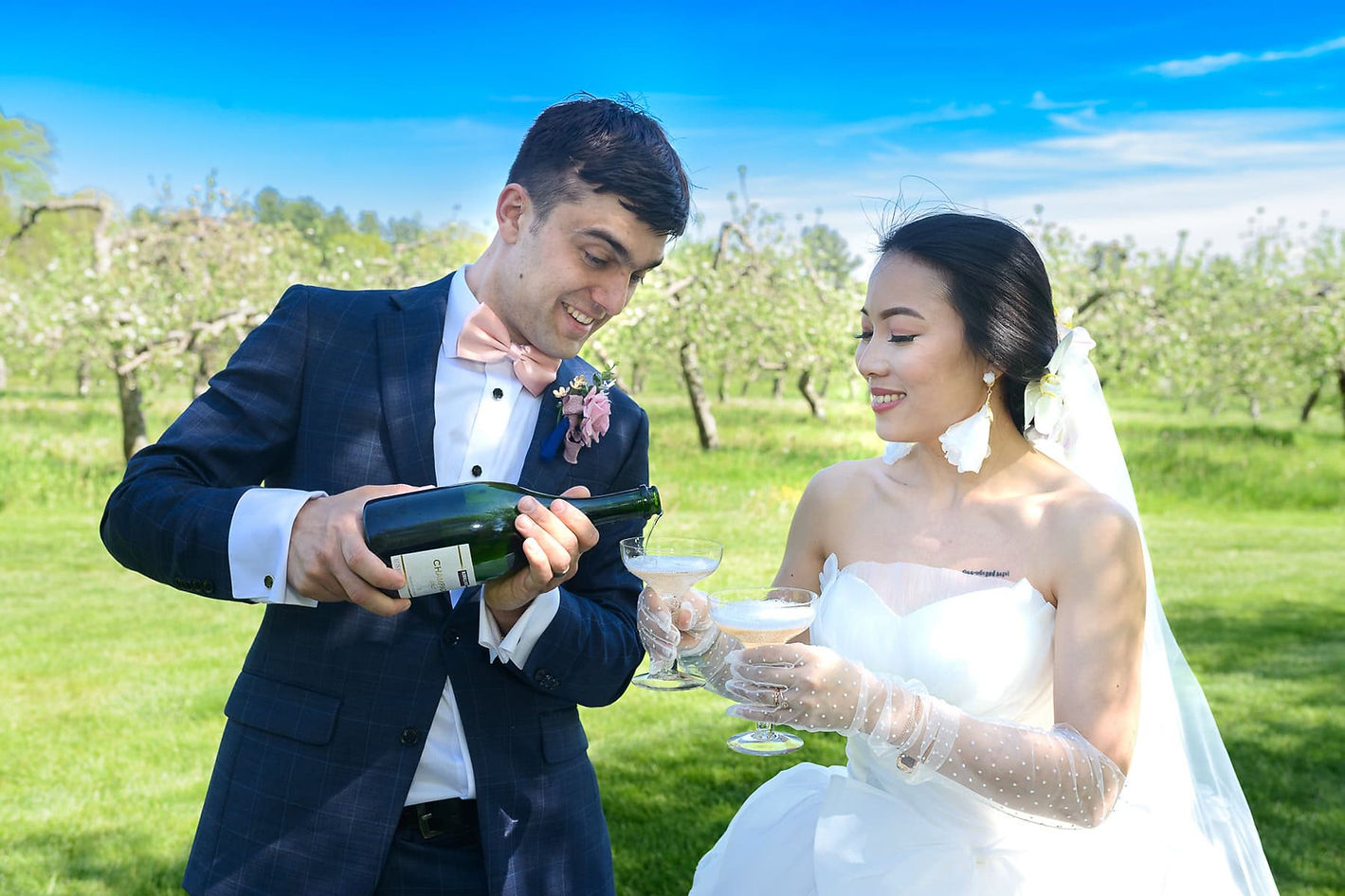 groom-pours-champagne-with-bride-outdoors.jpg