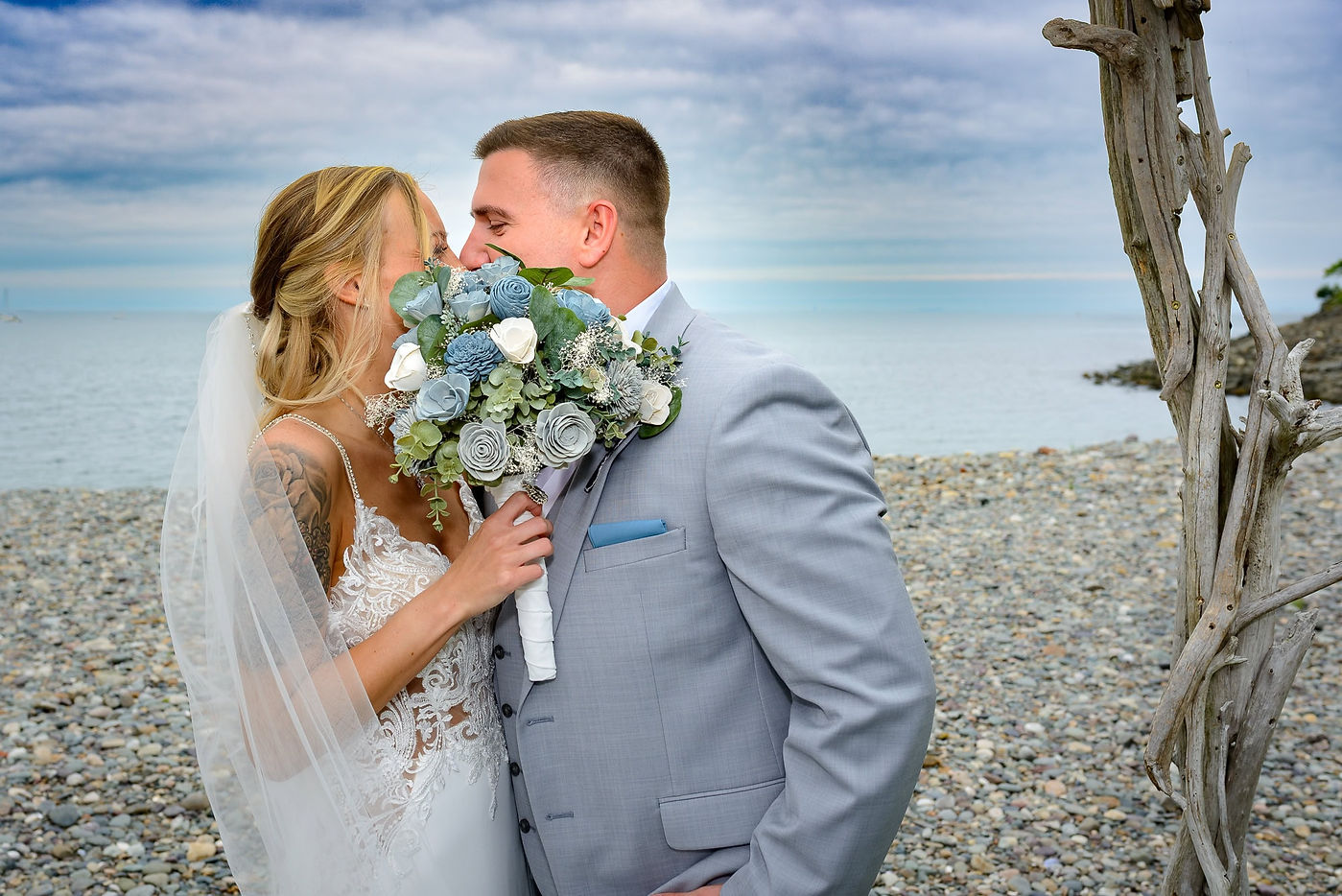 ocean-beach-wedding-newlyweds-kiss-behind-bouquet.jpg