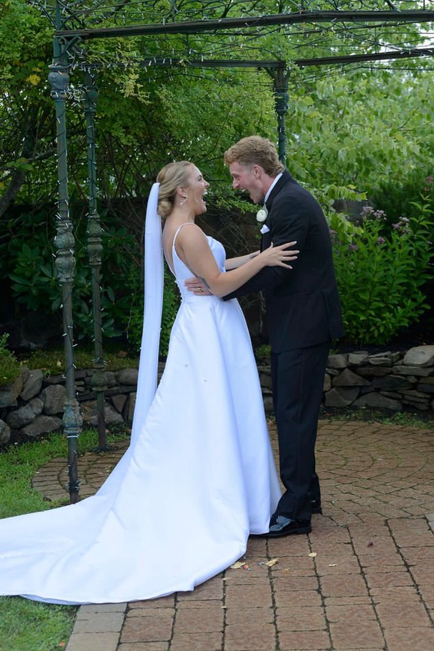 Bride and groom just married laughing together outdoors.