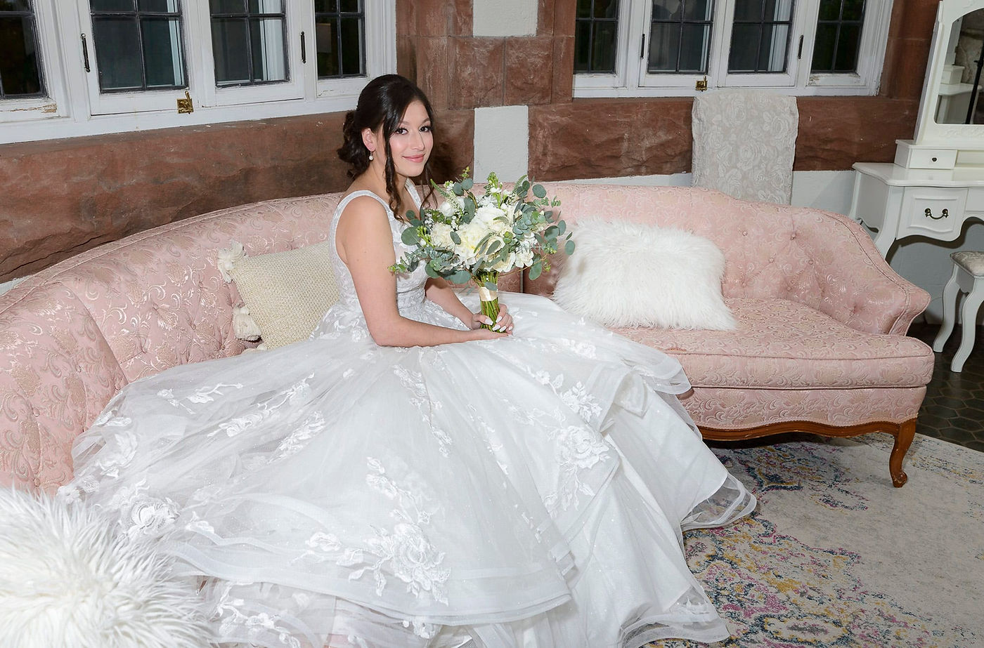 bride-sitting-on-pink-couch-in-a-voluminous-dress.jpg