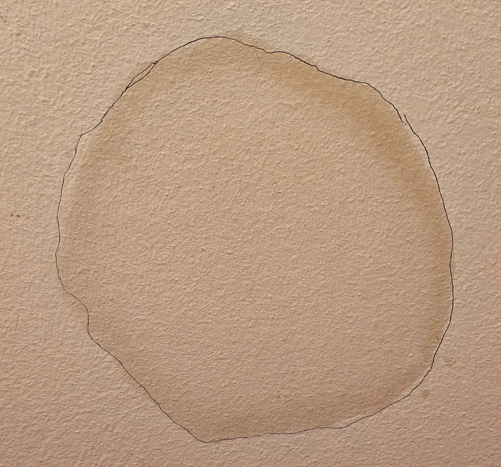 Wall with a large, irregular, discolored circle stain against a textured beige surface. The area is outlined, suggesting water damage.