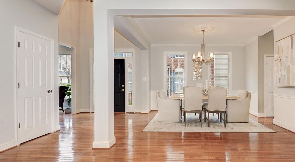 Elegant dining room with a table, chairs, and chandelier. Hardwood floors, light gray walls, and large windows. Calm, welcoming atmosphere.