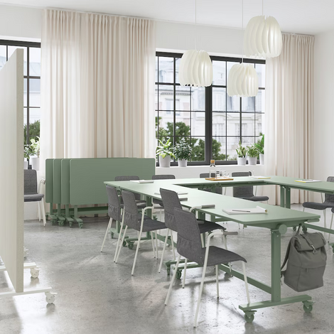 a classroom with green tables and chairs and white curtains