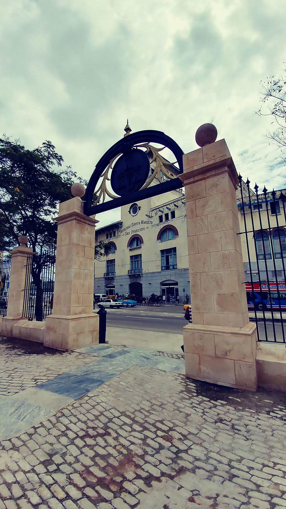 Entrance gate in Havana, Cuba, with cobblestone pavement and the Terminal Sierra Maestra San Francisco building across the street.