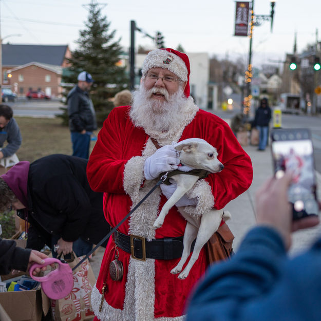Santa Claus holding small dog; Christmas event