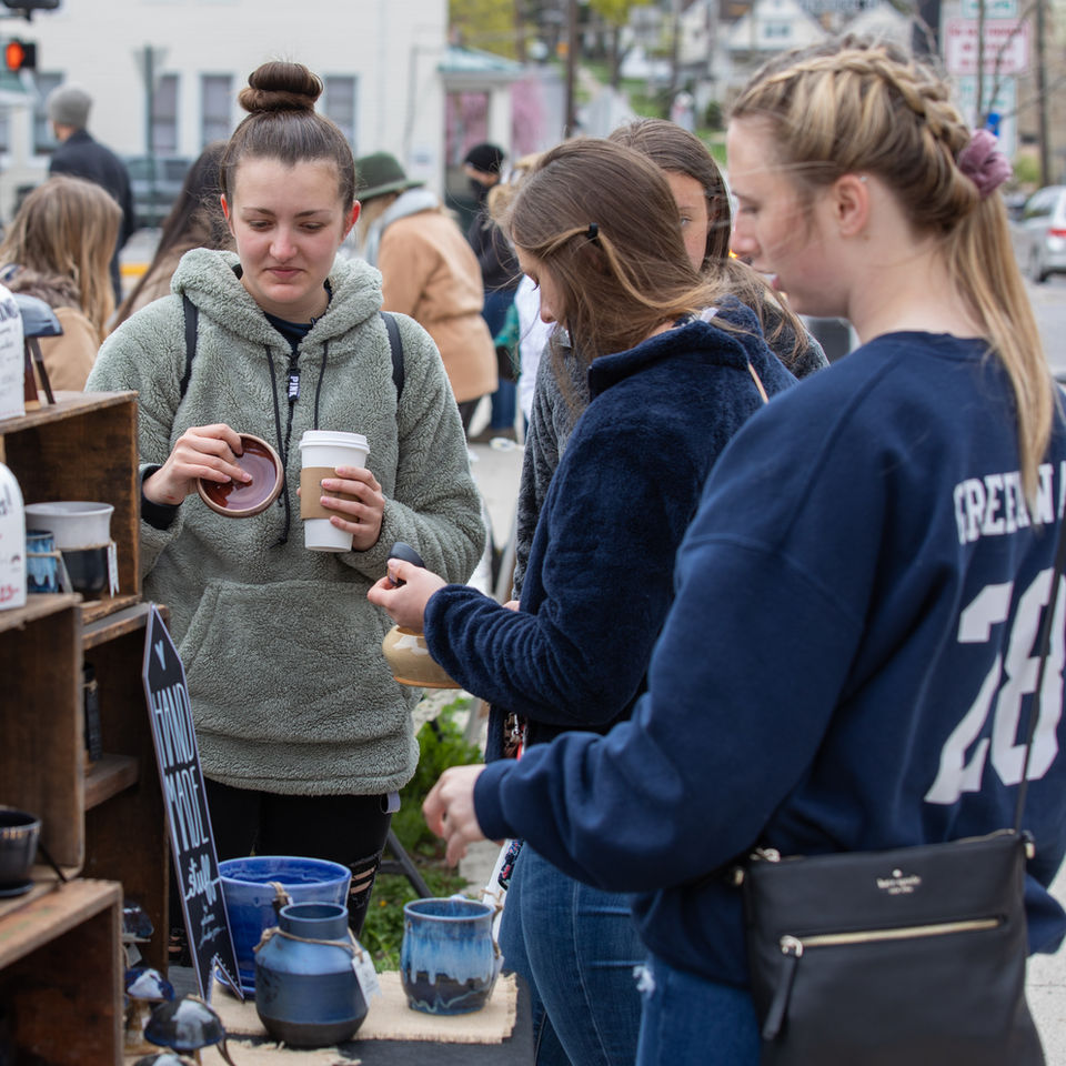 Customers browsing handcrafted pottery at outdoor market