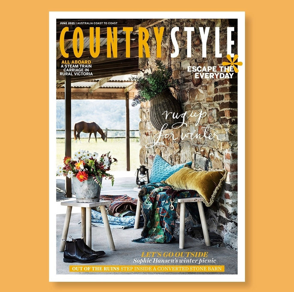 Front Country Style Magazine Cover June 2021. View of a verdah with stools and chairs laden with luxe pillow and rustic buckets of flowers. A horse is in the distance