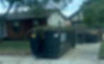 Close-up view of a dumpster with mixed yard waste and construction debris