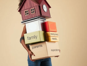 A woman who is overwhelmed carries boxes with words on them like family, parents, everyone's needs, expectations. Her face is obscured by the load