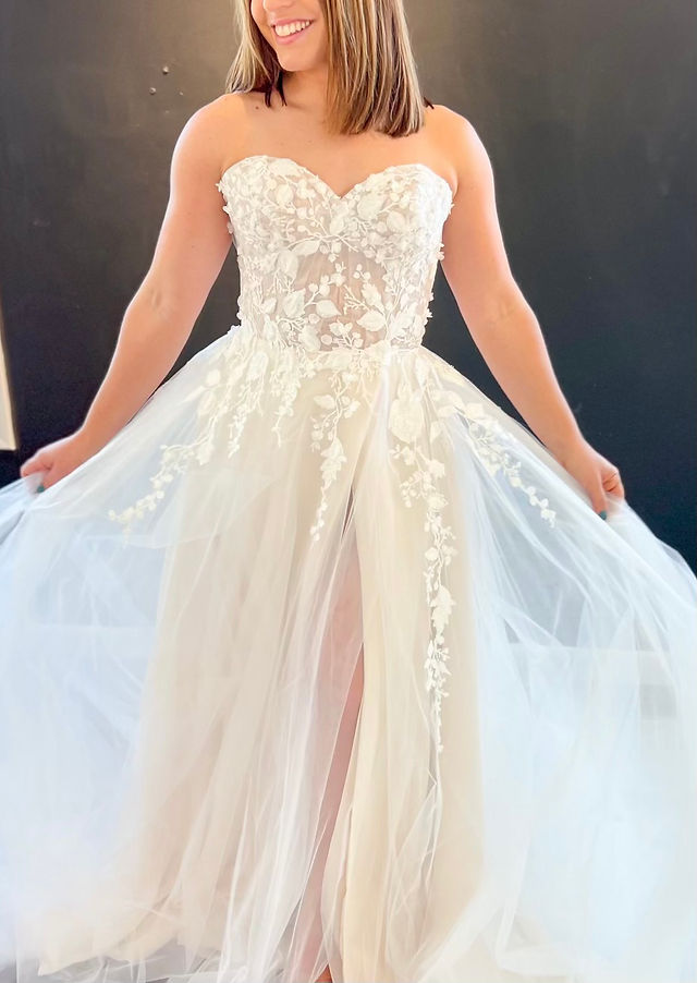 Bride wearing a sweetheart A-line wedding dress with floral appliqués and a flowy skirt during her appointment at Ever After Bridal Boutique