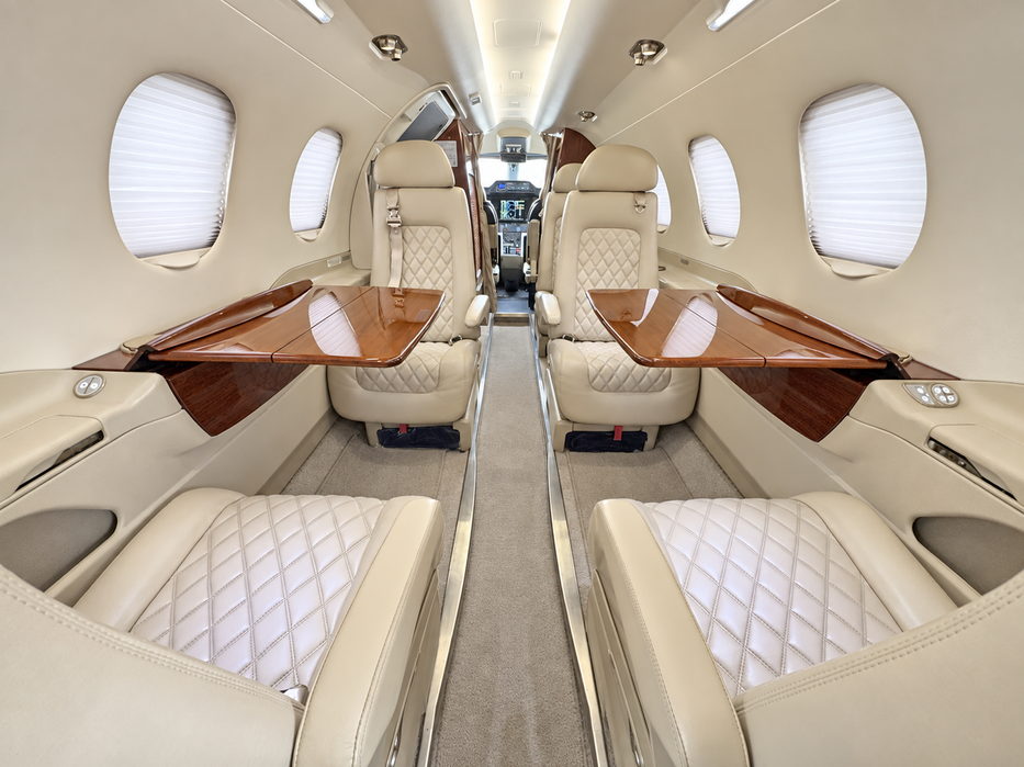 Cabine do Phenom 300 com poltronas club e mesas em madeira
