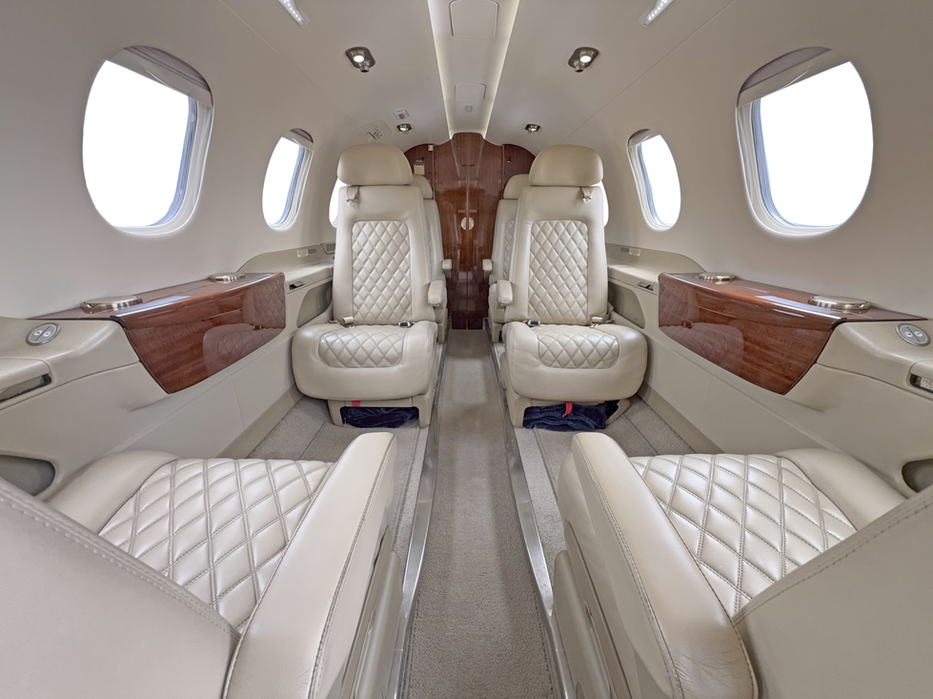 Cabine do Phenom 300 com poltronas em couro creme, vista para a traseira