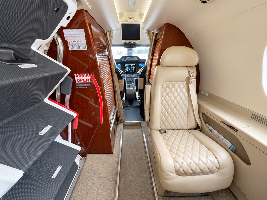 Poltrona dianteira do Phenom 300 ao lado do armário de bebidas
