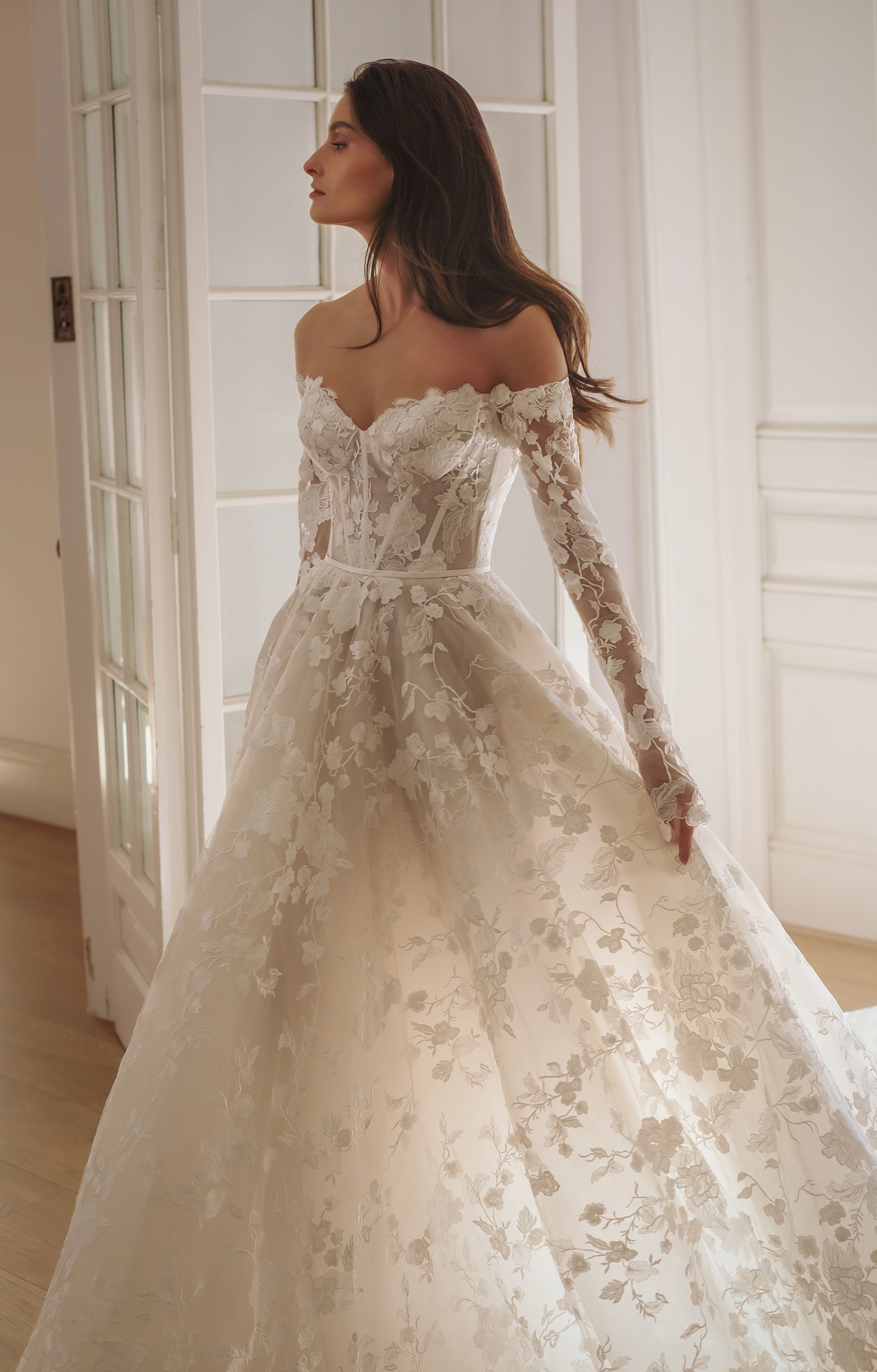 Opulentes Prinzessinnenkleid mit langen Ärmeln, floralen 3D-Applikationen und Nude-Unterton – märchenhafte Silhouette mit detailverliebtem Couture-Charakter.