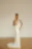 Lanvee von Eva Lendel: Auffälliges Mermaid‑Brautkleid, vollständig mit Kristall‑Perlen bestickt. Es ist trägerlos mit einer geraden Corsage, hat eine sichtbare, taillierte Corset-Konstruktion und einen optionalen, glatten Mikado-Overskirt mit großem Oversize-Bow am Rücken für einen königlichen Zweitlook.
