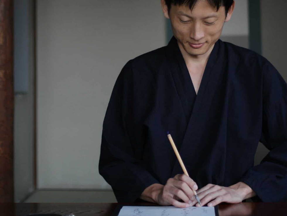 Japanese man writing with brush in traditional setting
