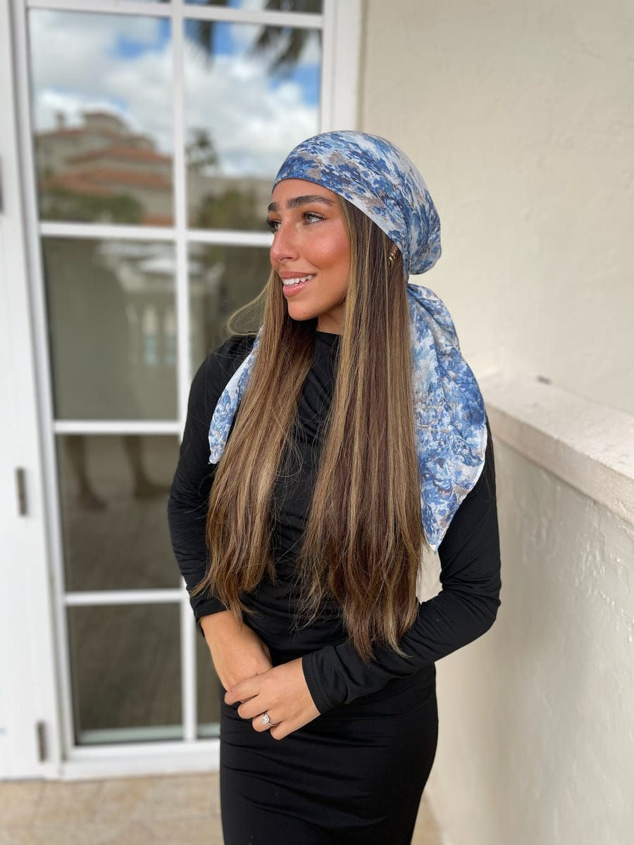 Woman wearing a Whimsical Blue Garden pretied tichel headscarf with long flowing tails in blue floral print.