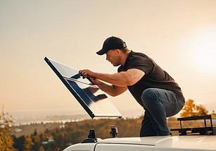 man installing a small solar panel on to the roof of a van .jpg