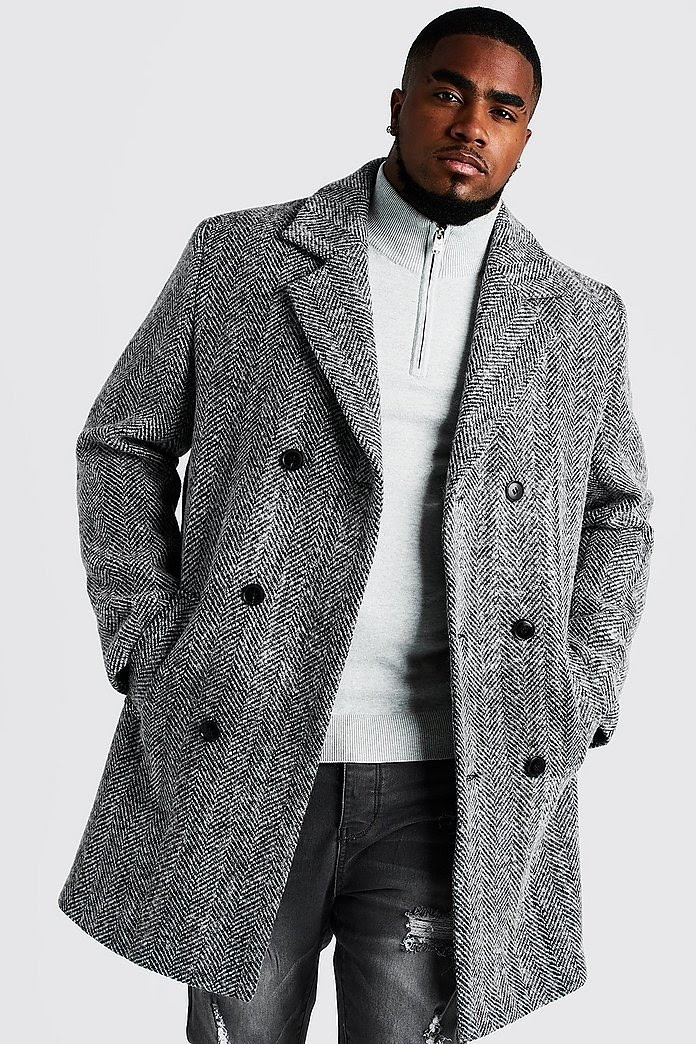 Man wears gray double-breasted wool blend overcoat to match his off-white sweater and gray jeans, a quality capsule piece