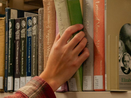 Kitaplıktan kitap alan bir insanın eli