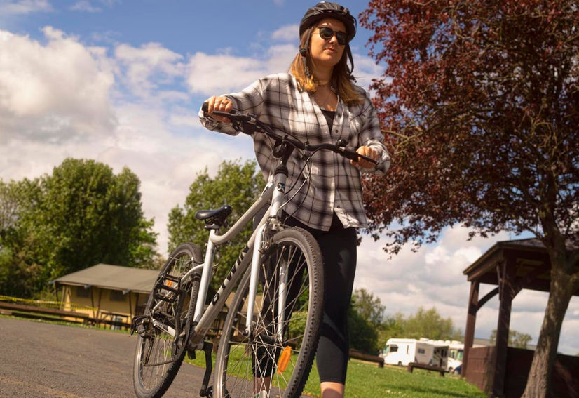 person wearing a cycling helmet pushing bike along tarmac surface