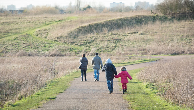 Four people walking along a surfaced pathway at Gunpowder Park