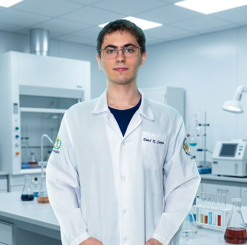 Studio photography of a scientist in a white lab coat standing in a laboratory setting. A clean, professional environment surrounds the subject with laboratory glassware visible in the background.