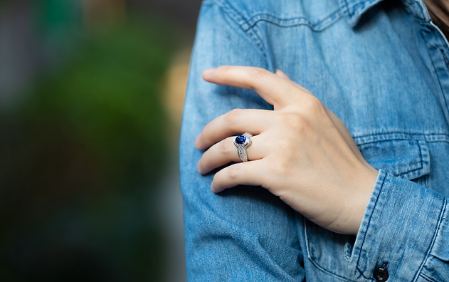 Sapphire ring with halo diamond setting styled with a denim jacket.