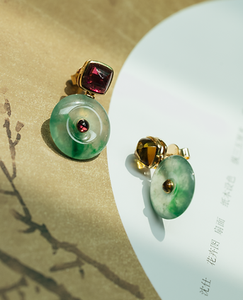 Still life photo of jade and tourmaline drop earrings styled on Chinese paper with calligraphy.
