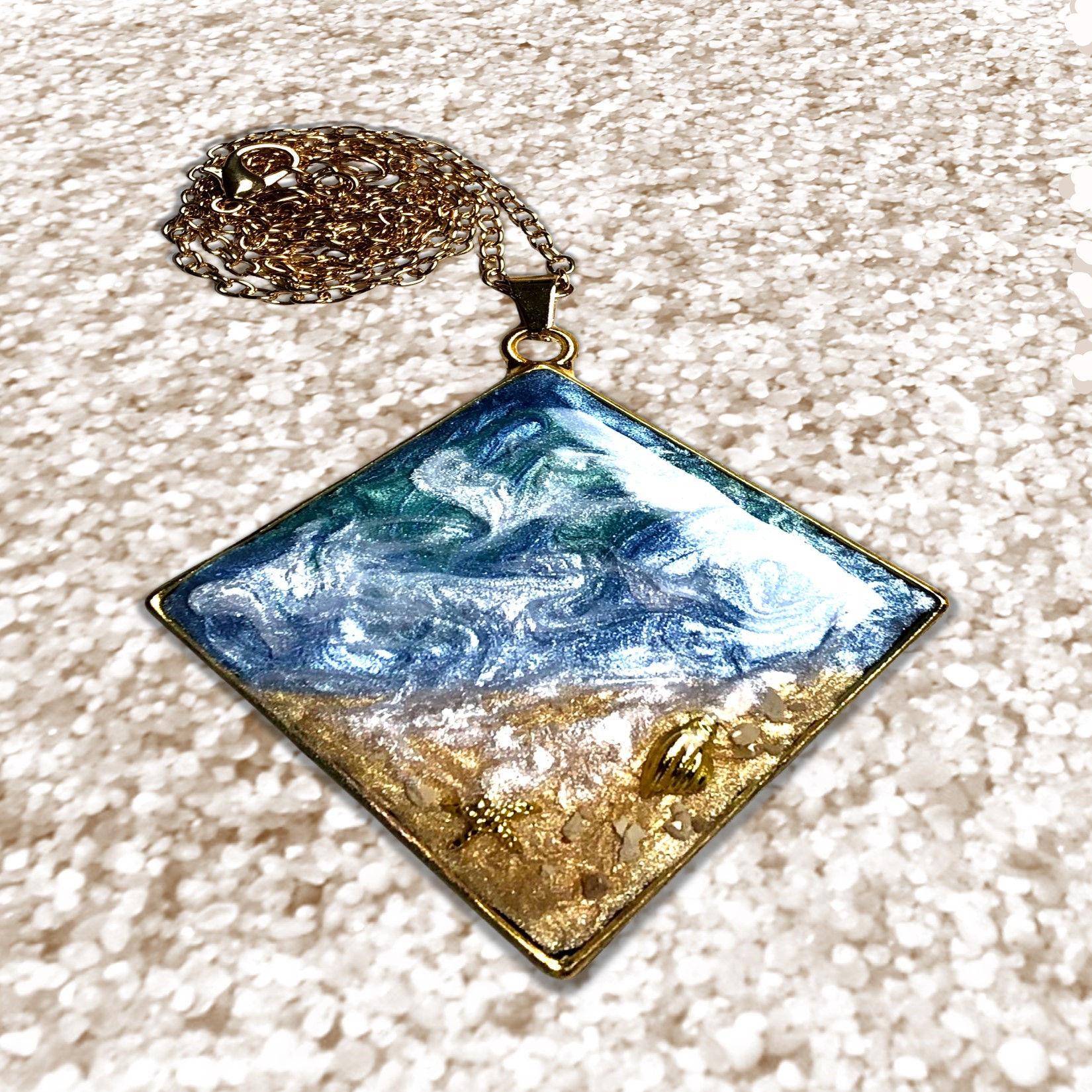 Diamond-shaped pendant with ocean scene, gold accents, and a delicate chain.