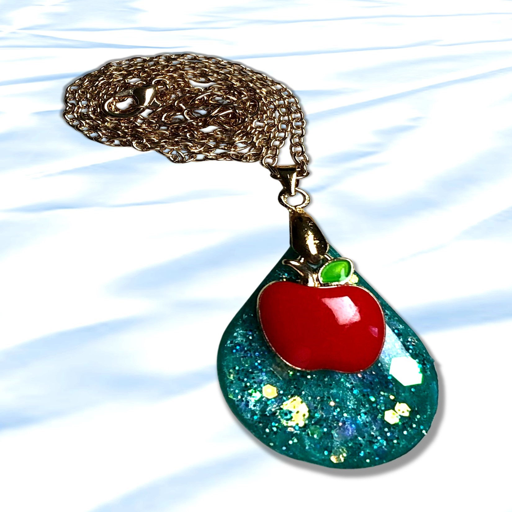 Gold Pendant Waterdrop Resin and Holographic with Apple Charm on a light background.
