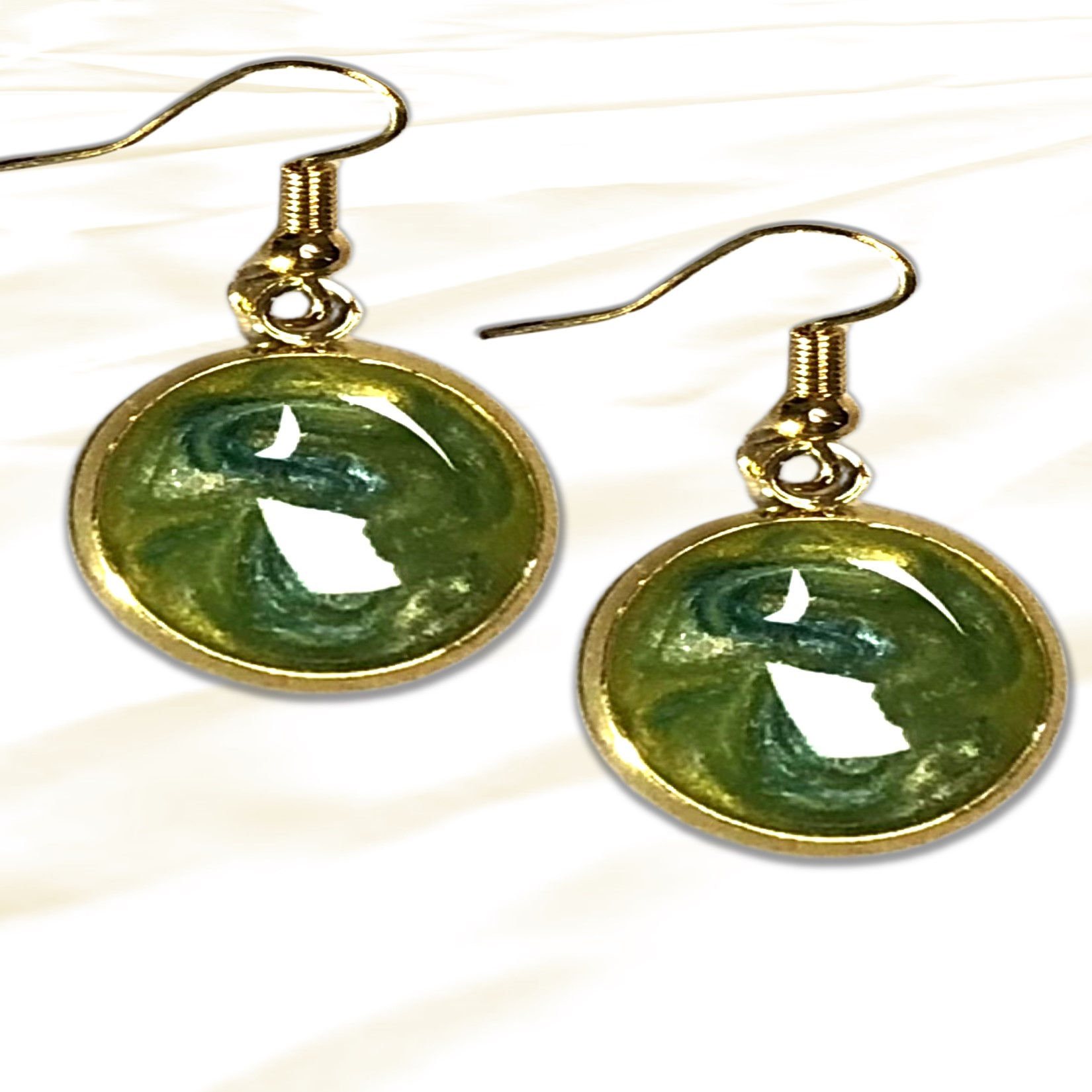 Pair of green earrings, gold hooks, round stones, white backdrop. KCM Gifts4You