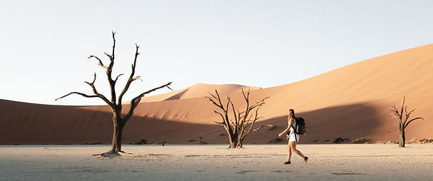 Traveler walking through golden desert dunes in Africa — embodying the spirit of adventure and bespoke safari experiences.