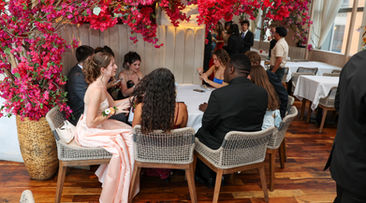Guests seated at dinner tables under pink flowers.