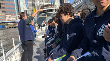 Students on boat learning, Harbor School boat, New York Harbor School, NYC buildings visible.
