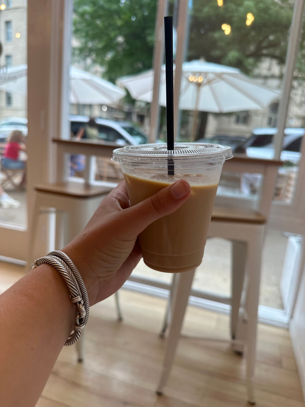 Iced vanilla latte on a wooden table inside Olor Coffee Bar.