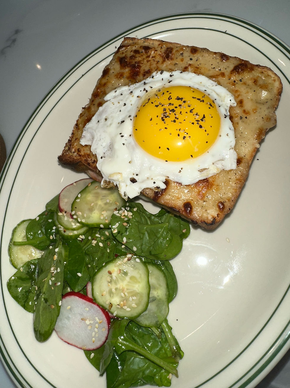 Croque Madame sandwich with melted gruyère, ham, and a poached egg on top.