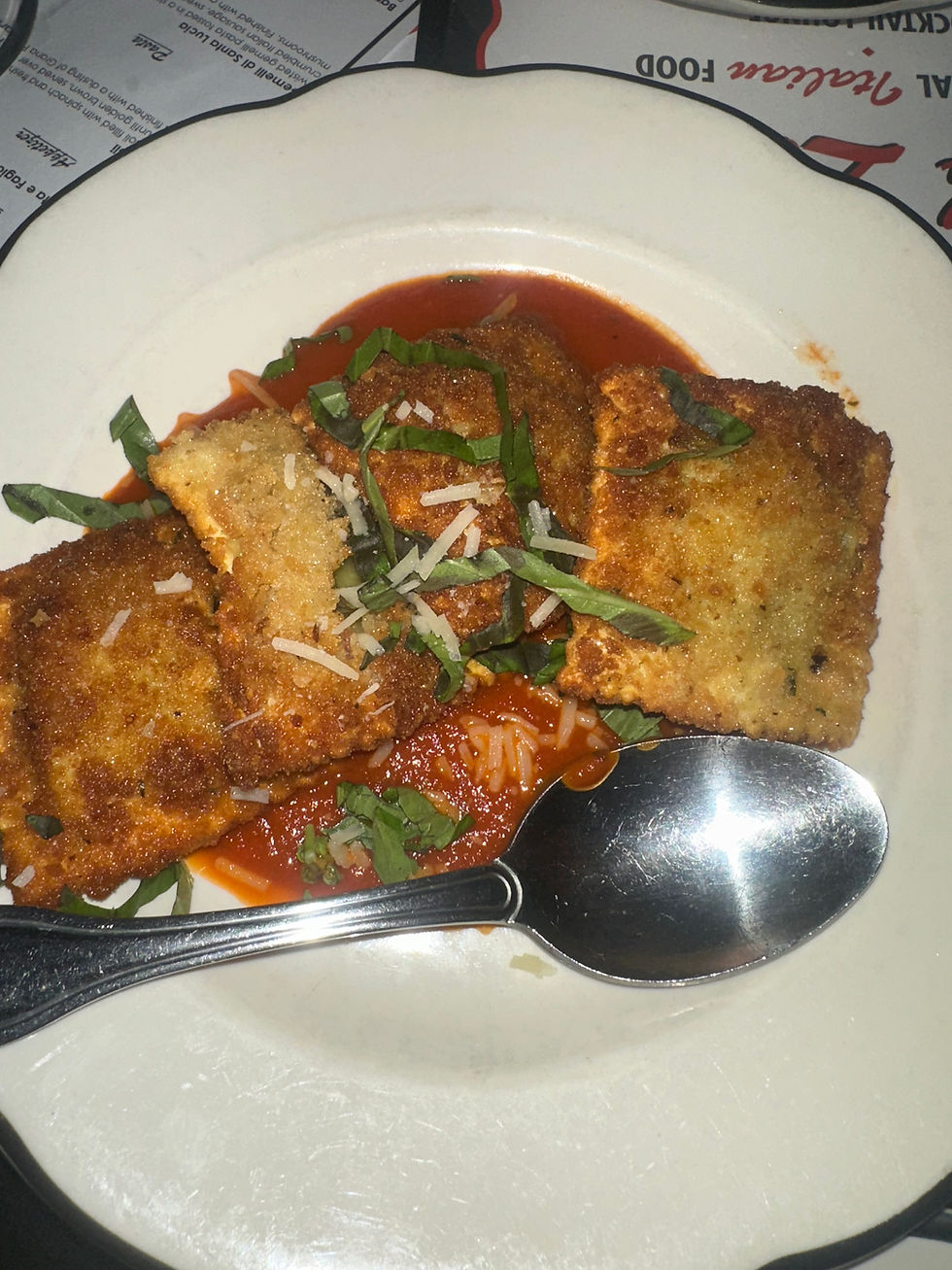 Fried ravioli appetizer served on a white plate with marinara dipping sauce.