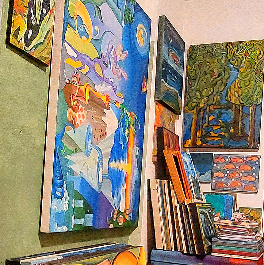 Foto de um canto com telas nas parede e pilhas de pinturas em tela no tema surreal no ateliê de Simone Lopes. Surrealismo e Modernismo.