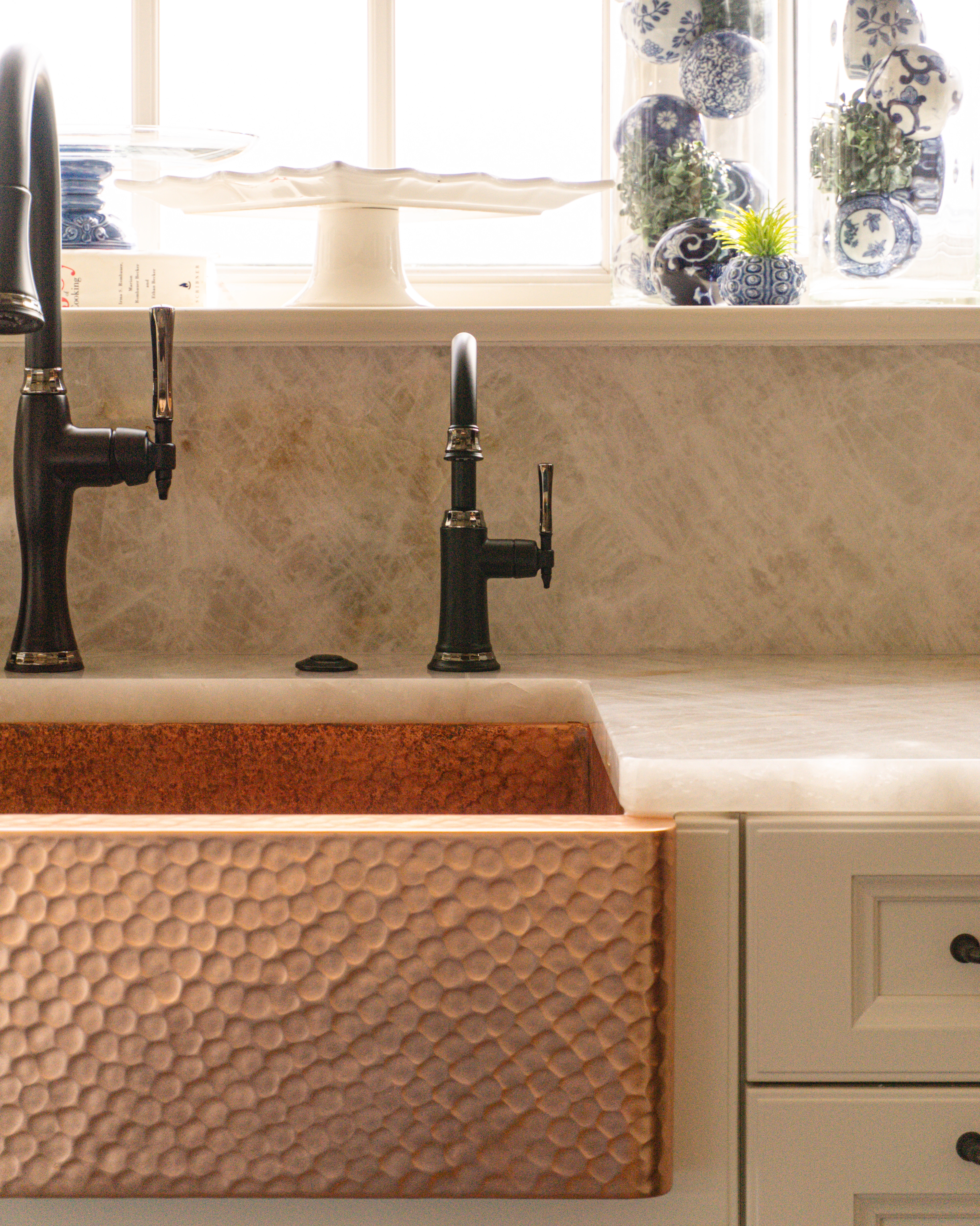 Cristallo Traslux Ultra Quartzite full-height backsplash and surrounding countertop next to and behind the sink, paired with a copper sink by Coppersmith Worldwide.