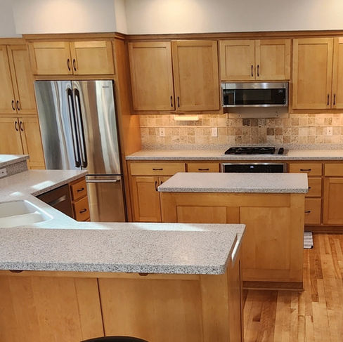 the before picture: Kitchen countertops and backsplash featuring Crystal Tempest Quartzite, a stunning natural stone with intricate patterns and hues of white, gray, and beige. The elegant surface contrasts beautifully with brown cabinets, creating a sophisticated and harmonious design in the kitchen space.