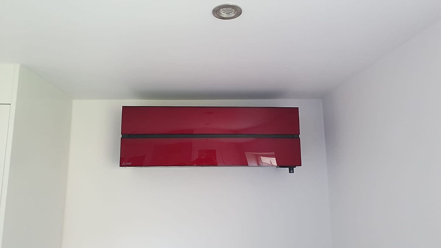 A sleek red air conditioner mounted on a white wall